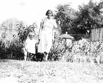 35 Hilda Meyers Adams and son, Donald Ross Adams In back yard of home in Allentown. In background is house & outhouse of Earl Cady's parents home. Oil well was...